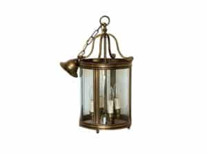 Vintage brass and glass hanging lantern with three candle-shaped light bulbs inside.