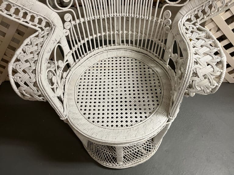 A Vintage Hollywood Regency Style Peacock Chair features intricate wicker weaving and a circular seat, set on a gray floor.