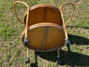 Two wooden chairs stacked upside down on grass, with visible metal wheels and handles.