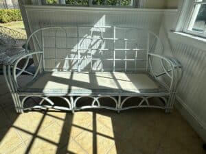 White metal-frame bench with sunlight casting patterns, placed on a tiled floor near large windows.