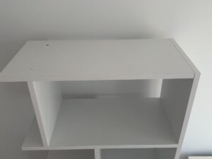 A white, empty shelf unit against a plain white wall, viewed from an angle above.